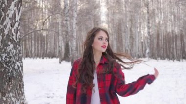 Karlı ormanda yürüyen uzun saçlı çekici bir kadın.