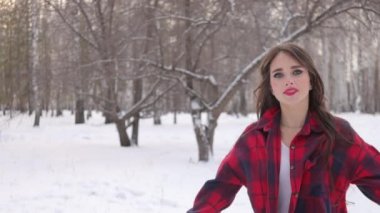 Karlı ormanda yürüyen uzun saçlı çekici bir kadın.