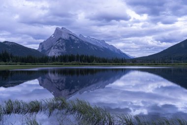 Kanada 'da karamsar bir gün batımı. Dağlar göl, yüzey, Banff Ulusal Parkı, Kanada' yı yansıtıyor.