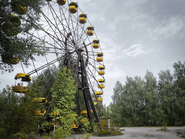 Ukrayna 'nın terk edilmiş Pripyat şehrinde sarı kulübeleri olan paslı bir atlıkarınca. 