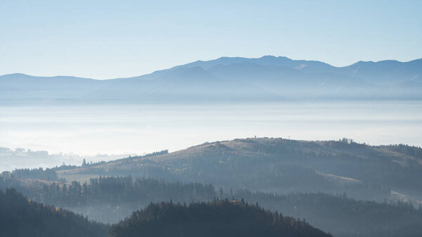 Осенний пейзаж с туманными лесами и туманными горами на заднем плане, Словакия, Европа.