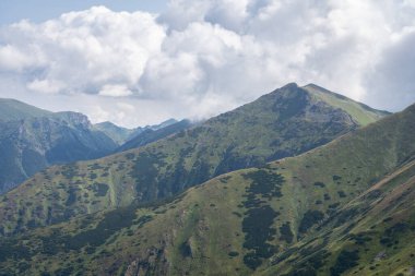 Üzerlerinde kalın bulutlar bulunan çimenli dağların katmanları, Slovakya, Avrupa.