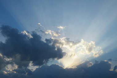 Gökyüzünde güzel gün batımı manzarası, bulutlarda güneş ışınları parlıyor.