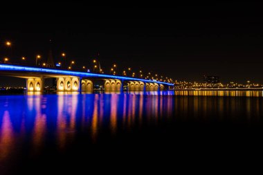 Dubai, Birleşik Arap Emirlikleri - 28 Mayıs 2022: Dubai 'deki Business Bay Crossing Köprüsü' nün gece görüşü. Suda bir sürü renk ve yansıma var..