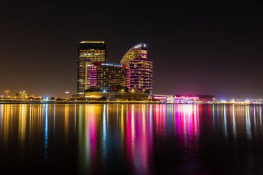 Dubai, Birleşik Arap Emirlikleri - 28 Mayıs 2022: Dubai Festival Şehri Gece Görüşü. Hotel Crown Plaza ve otelin kıtalararası binalarının manzarası. Sudaki renkler ve yansımalarla dolu.