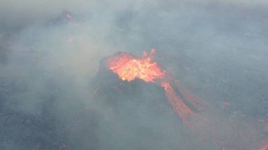 Aerial view through smoke, of a spawning lava basin - still, drone shot