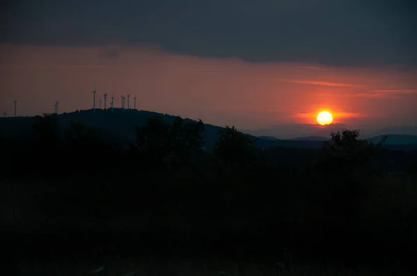 Wind turbines generate electricity at night. The sun goes down. Silhouettes, wind turbines, clean energy at night