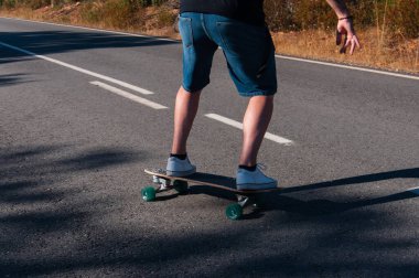 young man with skateboard, man on surf skate, surfing the highway, in a small town , nature