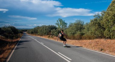 young man with skateboard, man on surf skate, surfing the highway, in a small town , nature