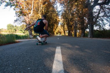 young man with skateboard, man on surf skate, surfing the highway, in a small town , nature