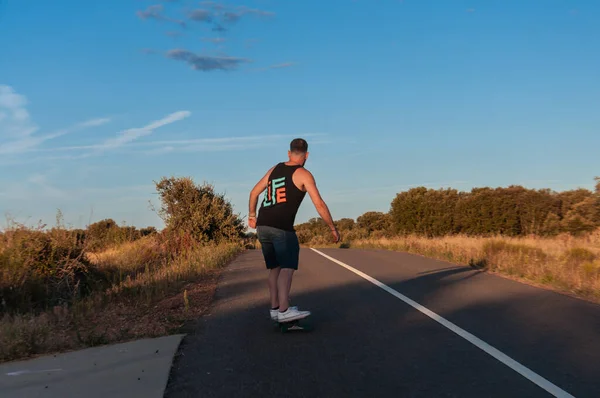 young man with skateboard, man on surf skate, surfing the highway, in a small town , nature