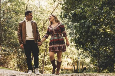 Aşıklar sonbahar parkında el ele yürür