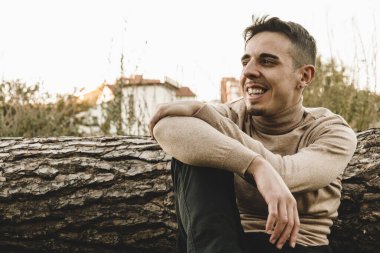 Genç adamın ön tarafı bir ağaç gövdesinin üzerinde oturuyordu.