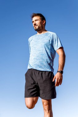 Mavi arka planda kuadriseps uzanan genç adamın amerikan çekimi