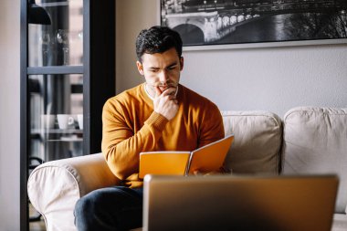 Düşünceli genç adam dizüstü bilgisayarda çalışıyor, problem çözmeyi düşünüyor, düşünceli erkek çalışan bilgisayar ekranına bakıp karar vermeyi düşünüyor.