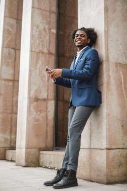 Genç Afrikalı Amerikalı iş adamı ofisin dışında cep telefonu kullanıyor.