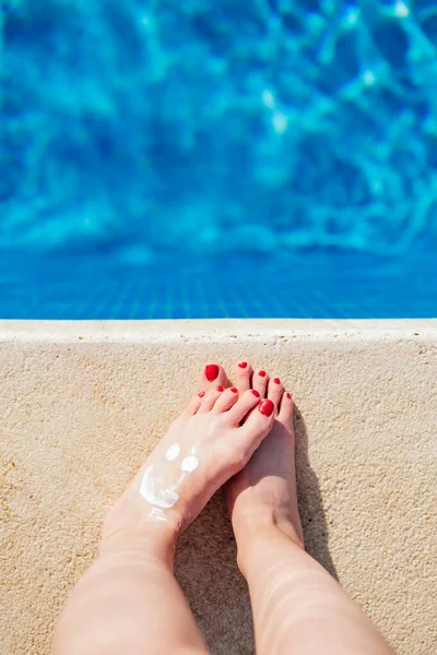 Güneş kremi sürmüş kadın ayakları, yukarıdan görüş, telif alanı, bacaklar bulanık, seçici odaklanma