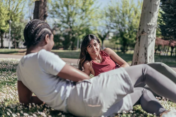 Joyful multiracial couple resting after jogging in park, she is looking at him — Stok fotoğraf