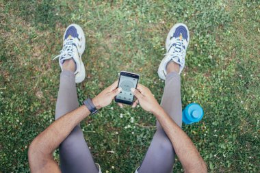 Yukarıdan, çalışan uygulamayı kullanan ve cep telefonunu kontrol eden genç adamın görüntüsü