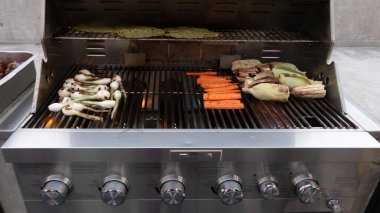 Gaz ızgarasında havuç, mısır ve soğan pişirmek.