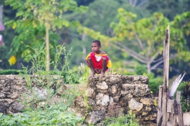 Sorong, Batı Papua, Endonezya, 29 Ekim 2021. Küçük bir çocuk ıssız bir vadide taş bir temele çömeliyor.