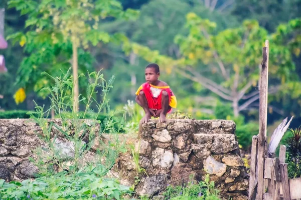 Sorong, Batı Papua, Endonezya, 29 Ekim 2021. Küçük bir çocuk ıssız bir vadide taş bir temele çömeliyor.