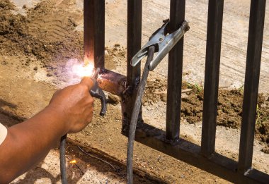 Bir işçi eldiven takmadan demir kaynaklıyor. Hafif kaynak çalışması.