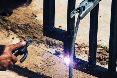 Bir işçi eldiven takmadan demir kaynaklıyor. Hafif kaynak çalışması.