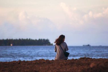 Sorong, Batı Papua, Endonezya, 19 Kasım 2021. Kumsalda tek başına akıllı telefonuyla kendi portresini çeken bir kız. Benim zamanım..