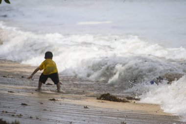 Sorong, Batı Papua, Endonezya, 12 Aralık 2021. Çocuklar sahilde dalgalara karşı oynuyorlar.