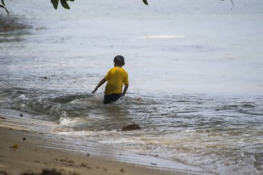 Sorong, Batı Papua, Endonezya, 12 Aralık 2021. Çocuklar sahilde dalgalara karşı oynuyorlar.
