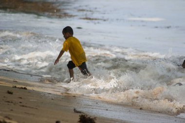 Sorong, Batı Papua, Endonezya, 12 Aralık 2021. Çocuklar sahilde dalgalara karşı oynuyorlar.