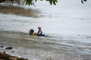 Sorong, Batı Papua, Endonezya, 12 Aralık 2021. Çocuklar sahilde dalgalara karşı oynuyorlar.