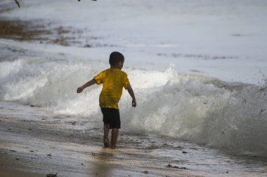 Sorong, Batı Papua, Endonezya, 12 Aralık 2021. Çocuklar sahilde dalgalara karşı oynuyorlar.
