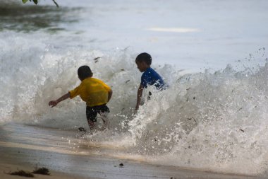 Sorong, Batı Papua, Endonezya, 12 Aralık 2021. Çocuklar sahilde dalgalara karşı oynuyorlar.