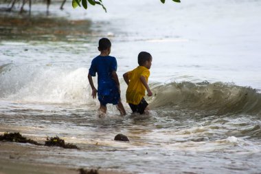 Sorong, Batı Papua, Endonezya, 12 Aralık 2021. Çocuklar sahilde dalgalara karşı oynuyorlar.