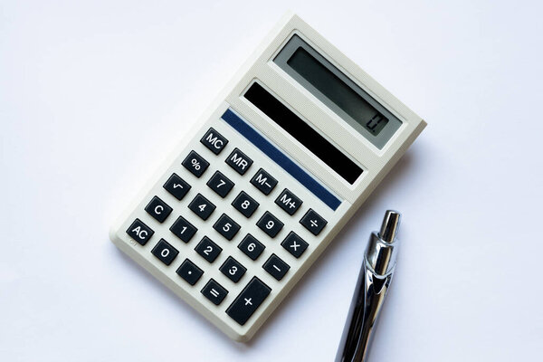 An overhead view of a vintage calculator and pen on a plain white background