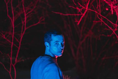 Arka planda arka lambalı bir adam, gece çekilmiş bir fotoğraf.