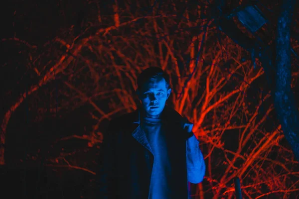 Arka planda arka lambalı bir adam, gece çekilmiş bir fotoğraf.