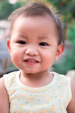 2 yaşındaki bir kız eğleniyor ve mutlu ve süt dişlerini gösteriyor..