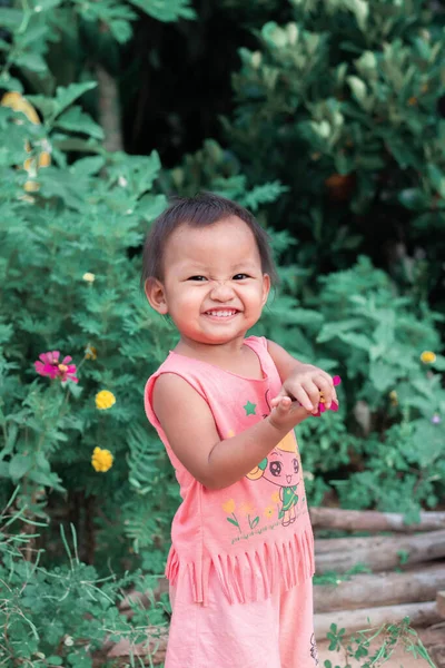 2 yaşındaki bir kız eğleniyor ve mutlu ve süt dişlerini gösteriyor..