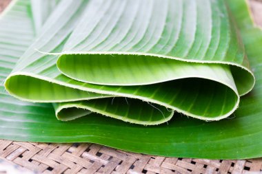 Green banana leaves arranged on a plate, bamboo tray. Banana leaf background.