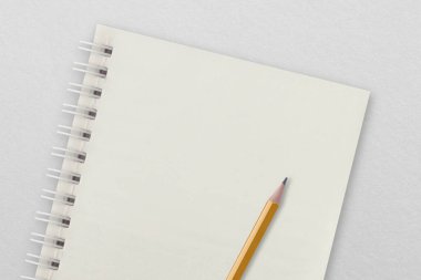 Beyaz kağıt yüzeyine yerleştirilmiş beyaz defter ve kalem. Not Defteri kavramı.