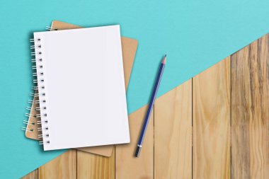 Kahverengi ahşap zemine dizilmiş defter ve kalem. Not Defteri kavramı.