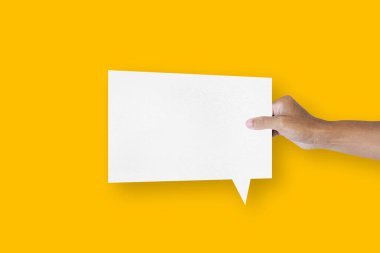 hand holding a square shaped white paper balloons speech bubbles isolated on yellow background communication bubbles.