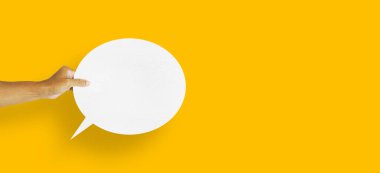 hand holding round white paper balloons speech bubbles isolated on yellow background communication bubbles