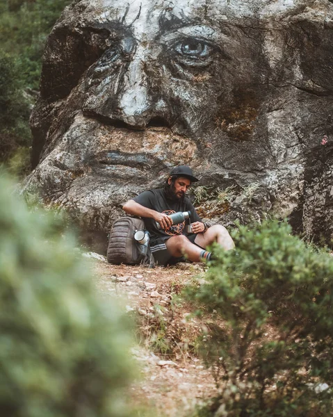 Yorgun bir gezgin kayanın dibinde su içiyor.