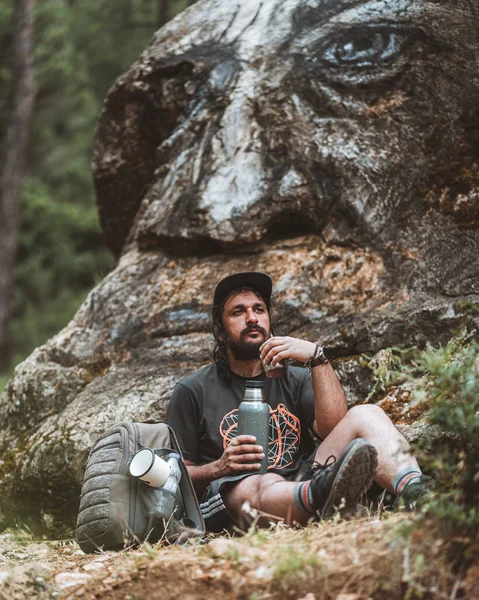 Yorgun bir gezgin kayanın dibinde su içiyor.