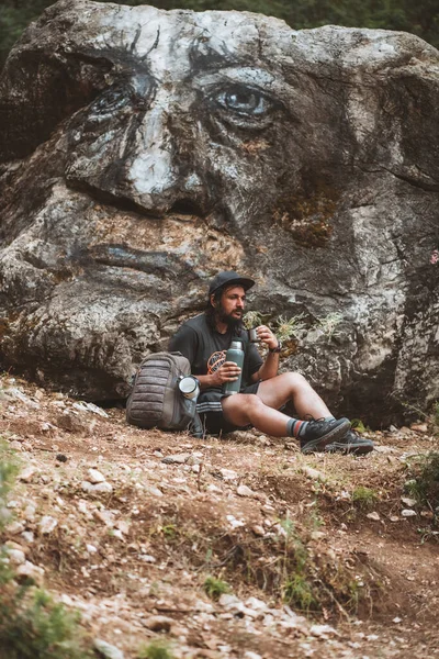 Yorgun bir gezgin kayanın dibinde su içiyor.