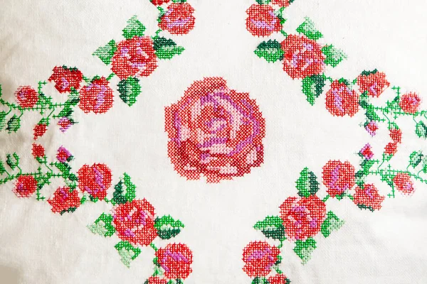 Декоративный элемент, крестообразная вышивка из розовых цветов, на белой льняной ткани. — стоковое фото